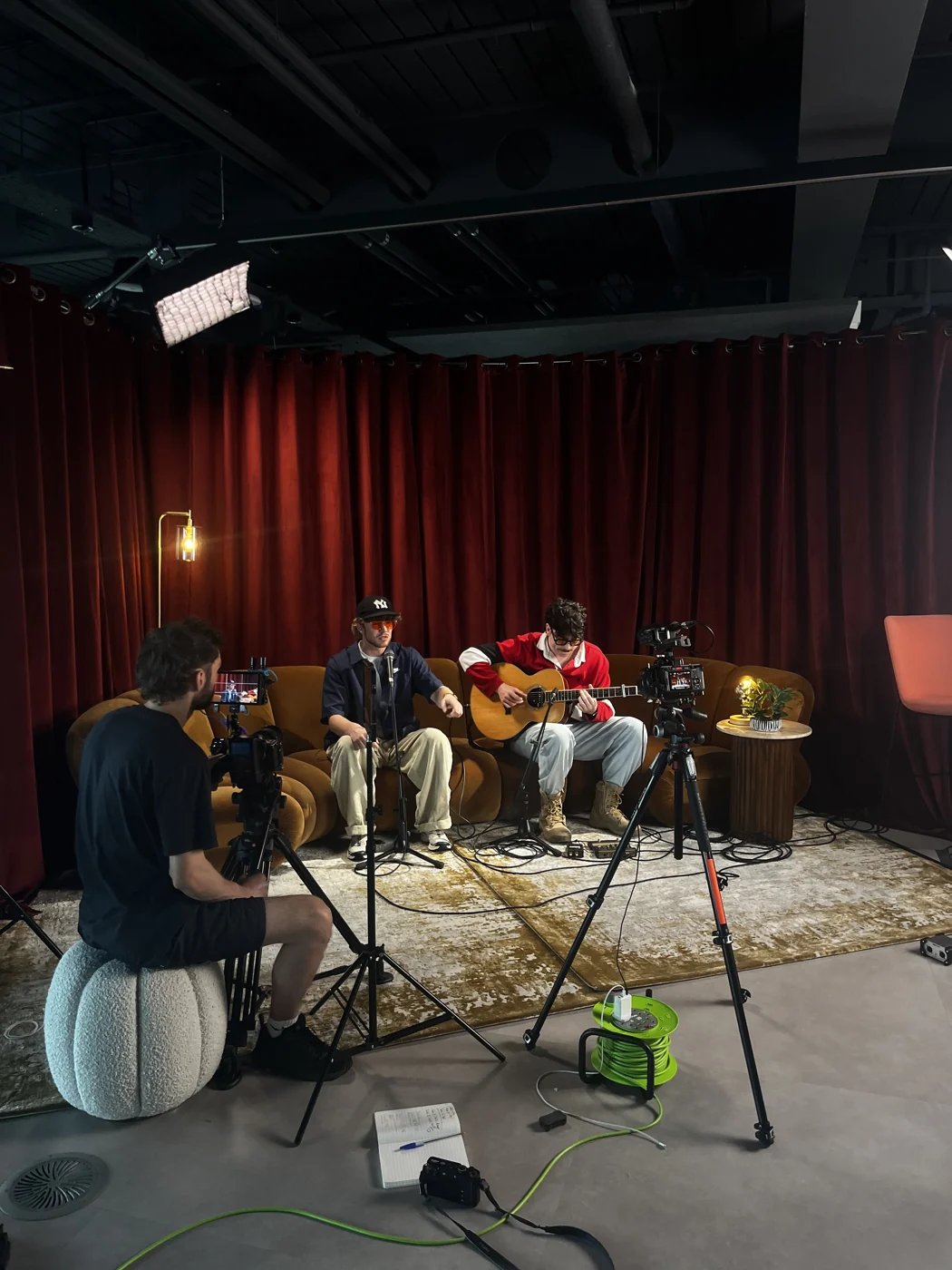 The team filming a live performance in front of red curtains